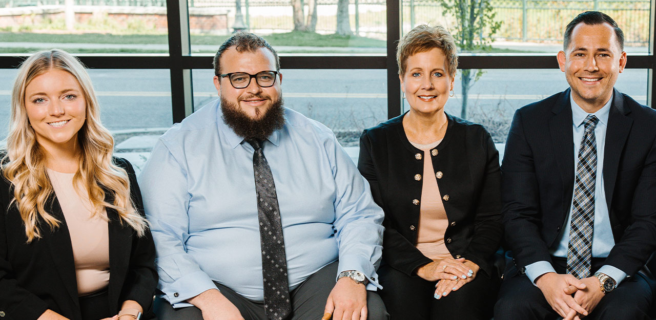 Alisha Kuch, Elijah Isch, Sheri Welsh, and Spencer Welsh smile while sitting side by side in front of a window.